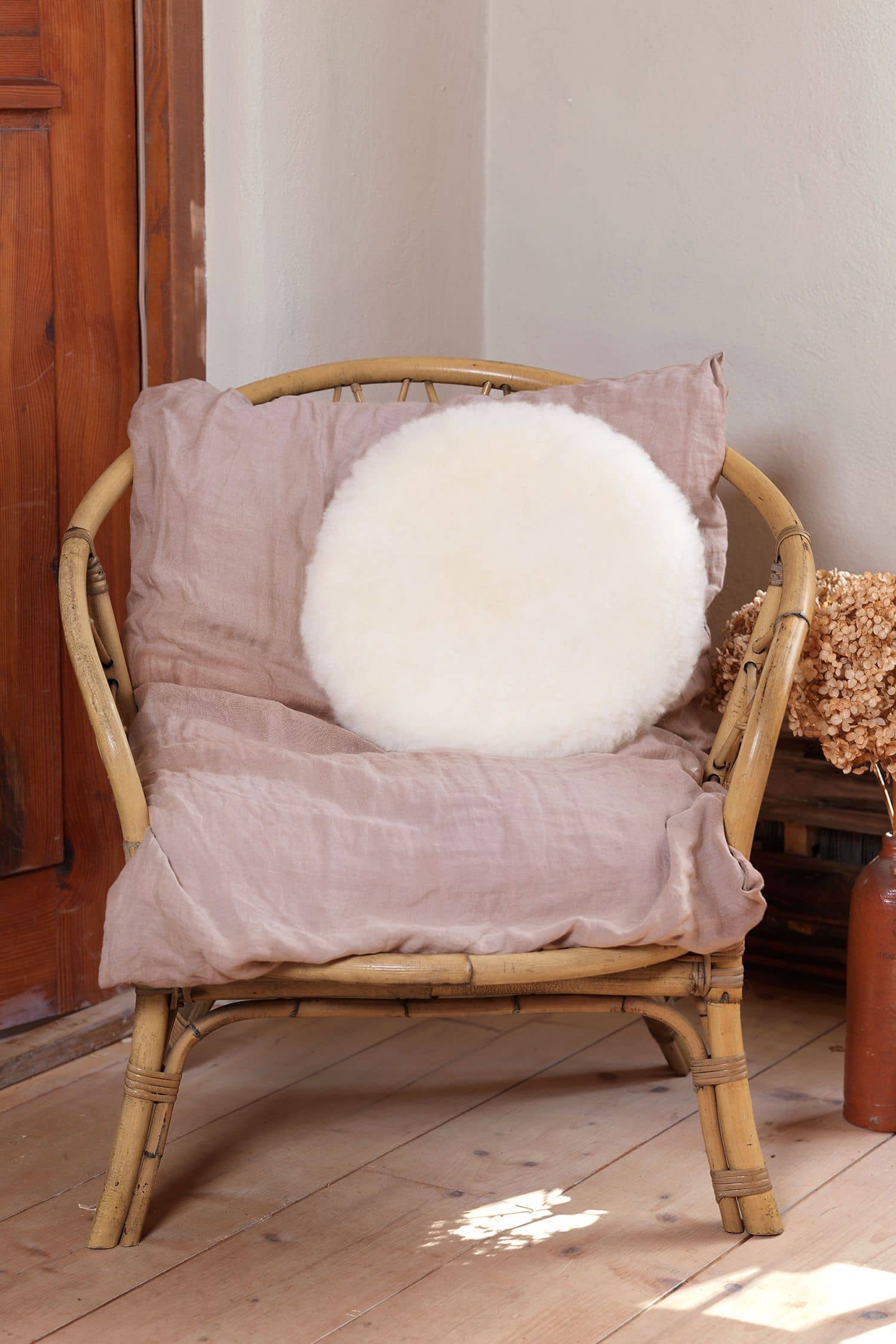 rundes Wohlfühlkissen aus pflanzlich gegerbtem Finkhof Fell liegt auf einem Korbstuhl