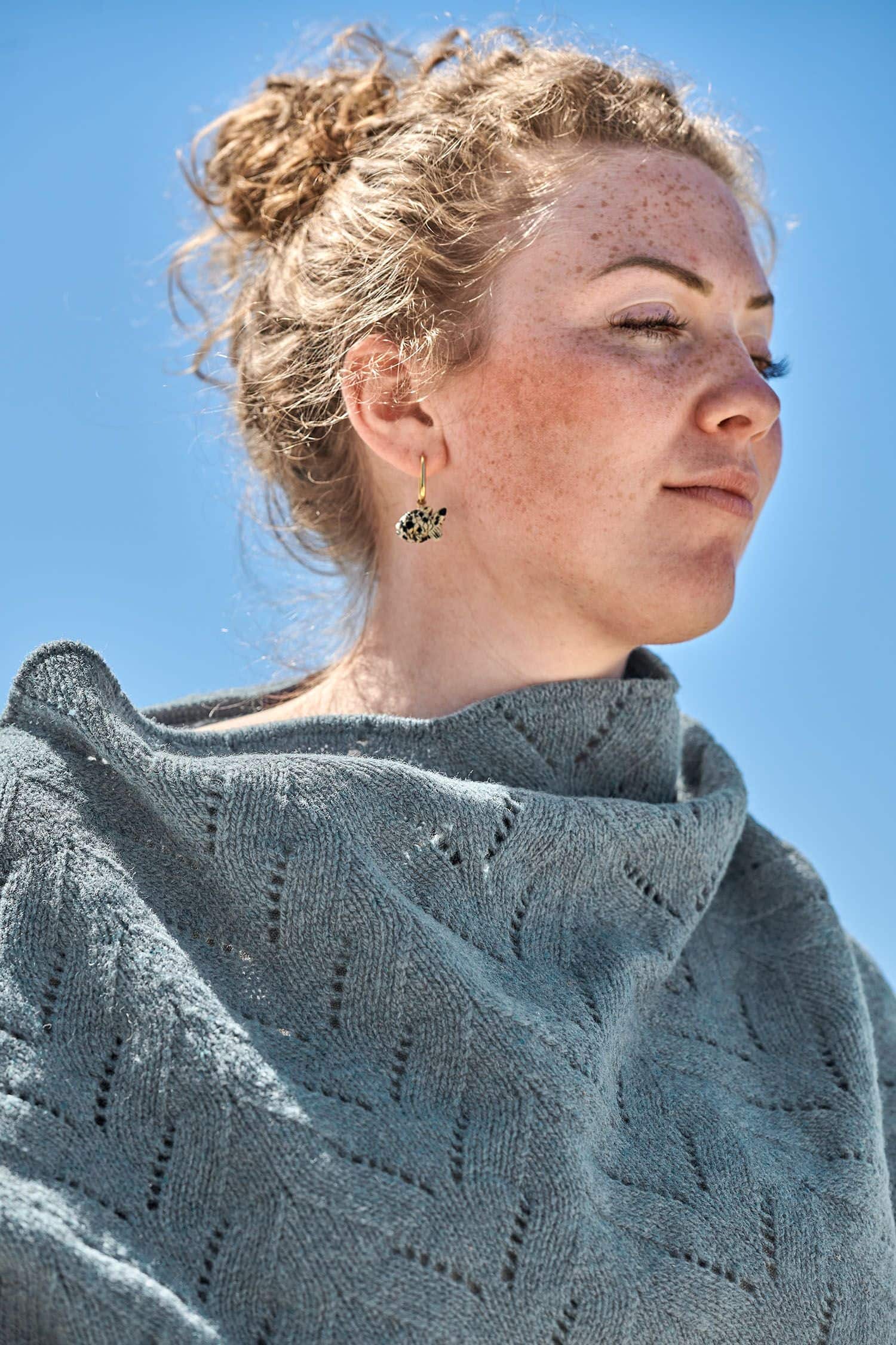 Frau trägt rauchblauen Finkhof Poncho aus bio Merinowolle (kbT) mit Ajourmuster