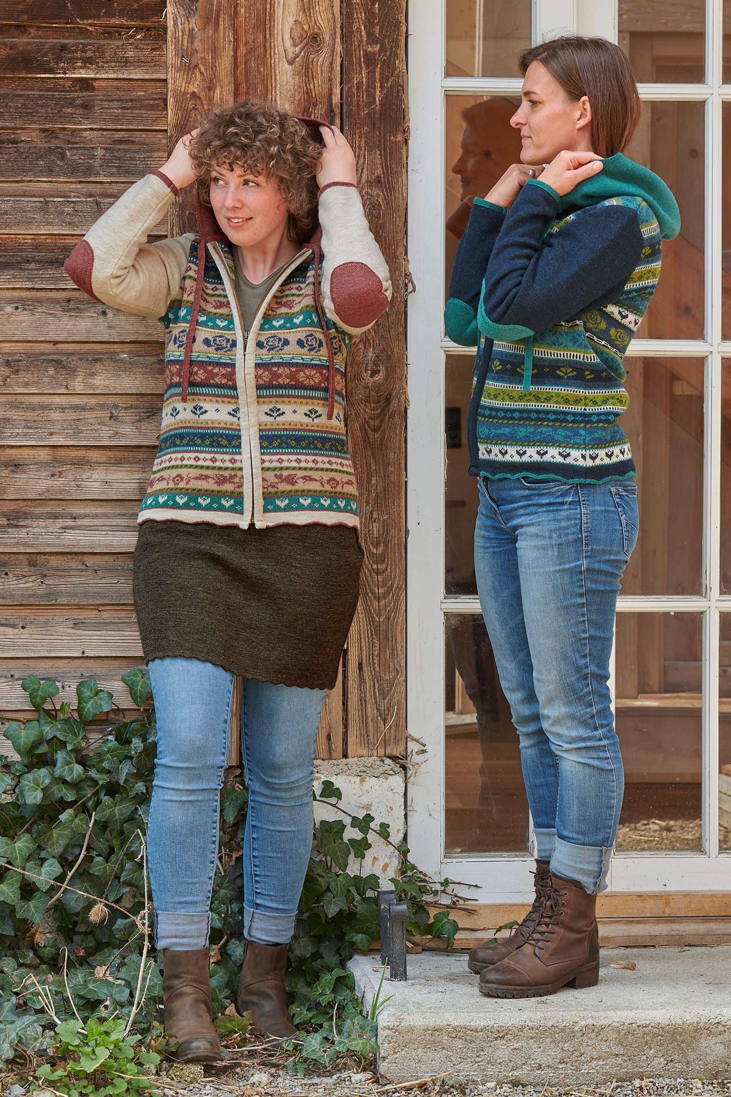 Jacke Jolanda Frauen tragen Jeans und gemusterte Jacke in rosa und blau aus bio Merinowolle (kbT) und stehen vor Holzhaus