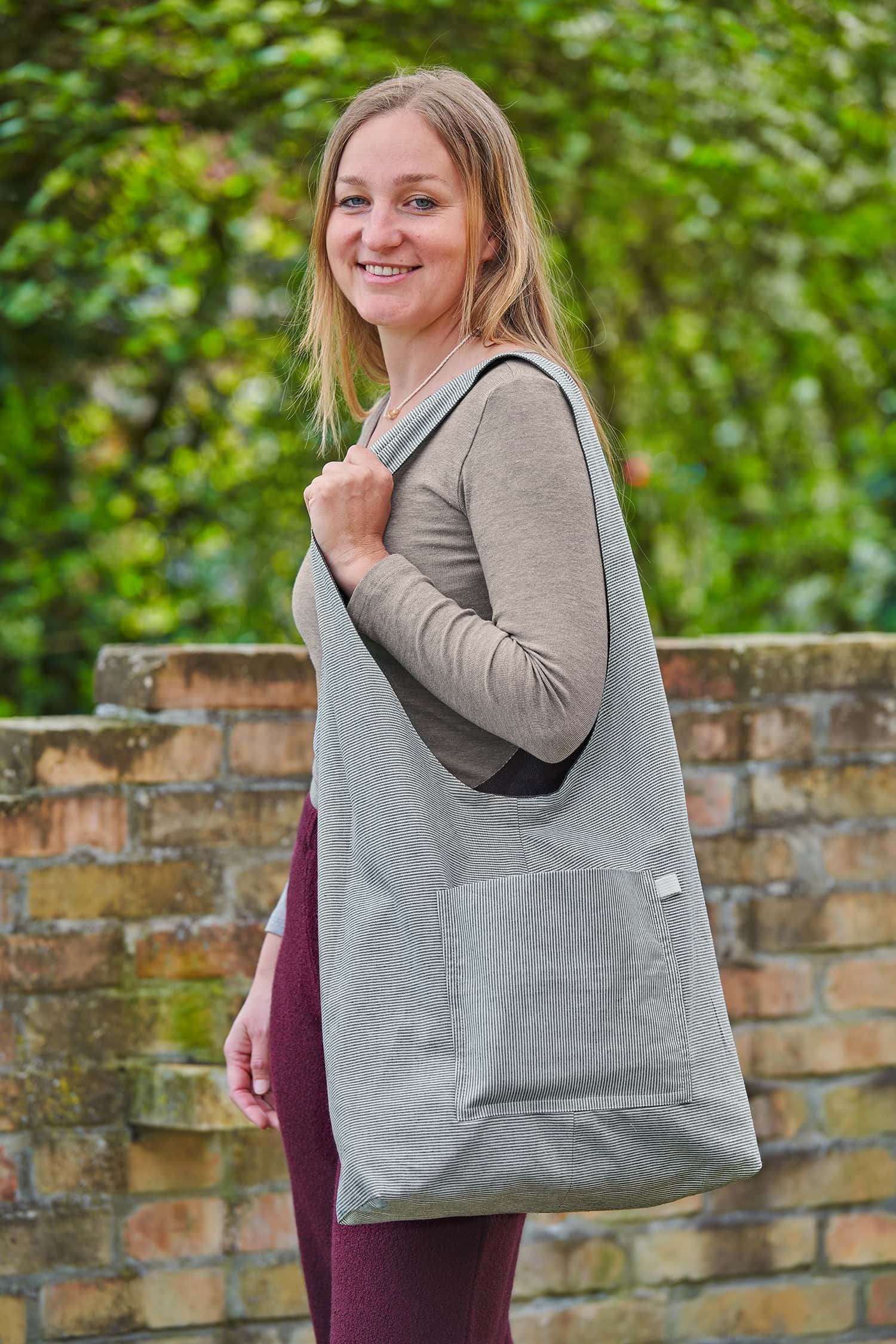 Frau mit Wollhose und Langarmshirt trägt einen gestreiften Shopper aus Bio-Baumwolle zum Wenden vom Finkhof