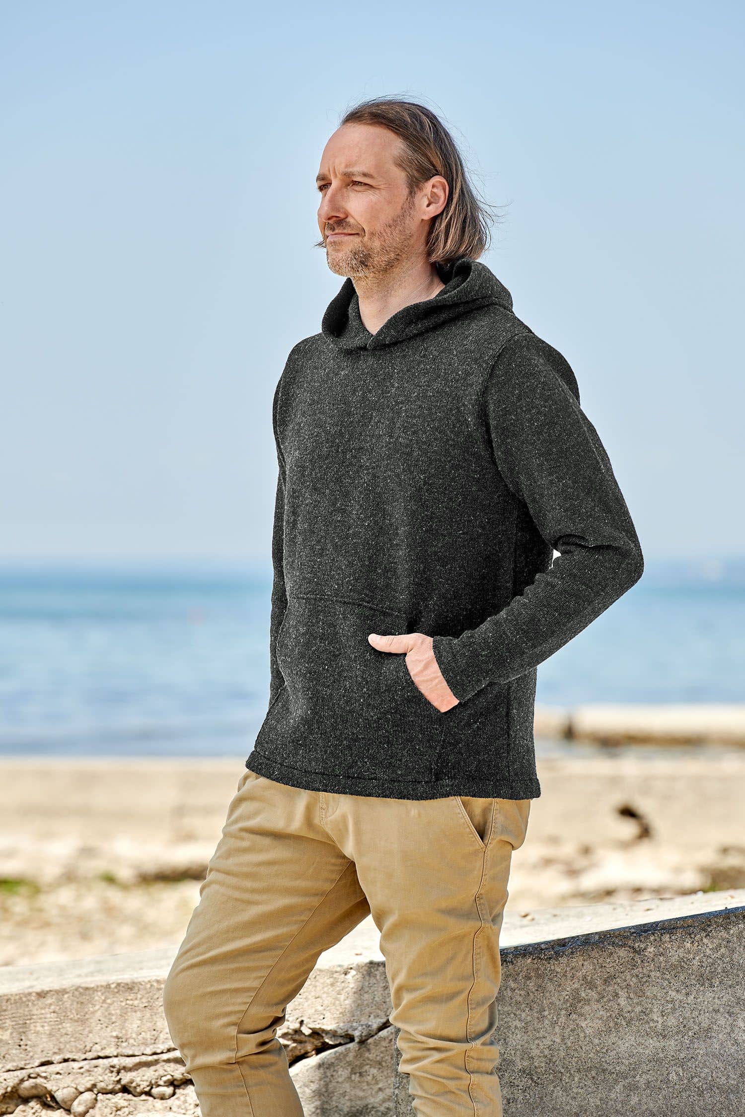 Mann trägt anthrazitfarbenen Kapuzenpulli aus bio Merinowolle (kbT) vom Finhkhof