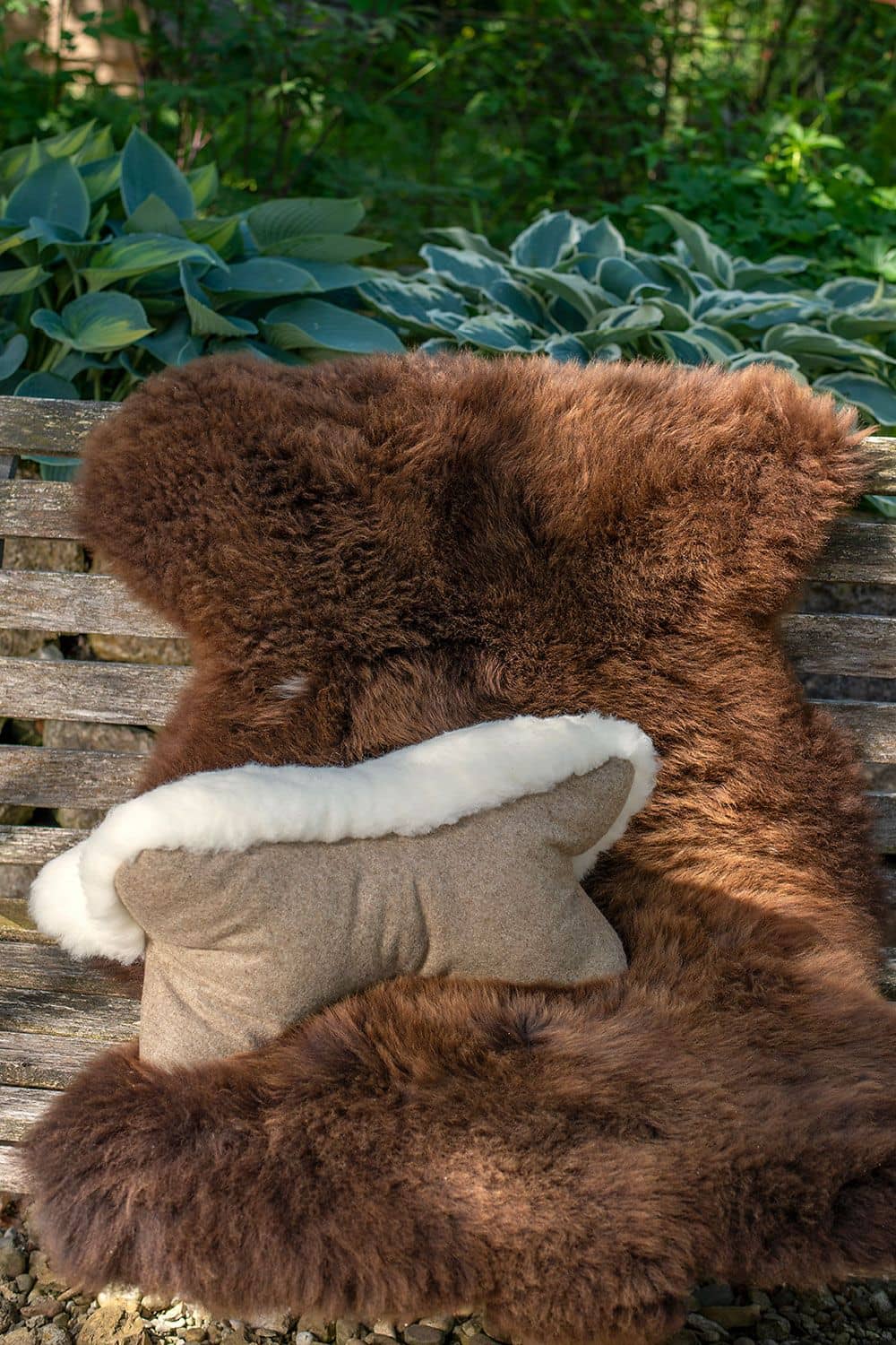 auf Holzbank liegt braunes Fell und Finkhof Leseknochen aus pflanzlich gegerbtem Schaffell, Loden und Rohwolle (kbT)