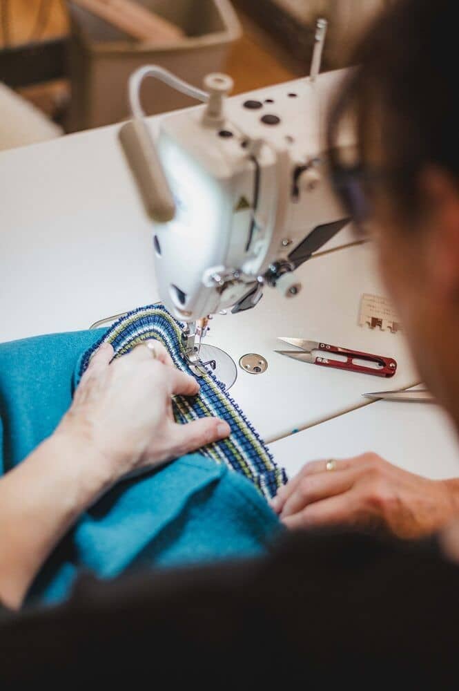 finkhof-manufakturen-stoffnaeherei-1 Annähen von einem gemusterten Bündchen an einen blauen Stoff in der Finkhof Näherei