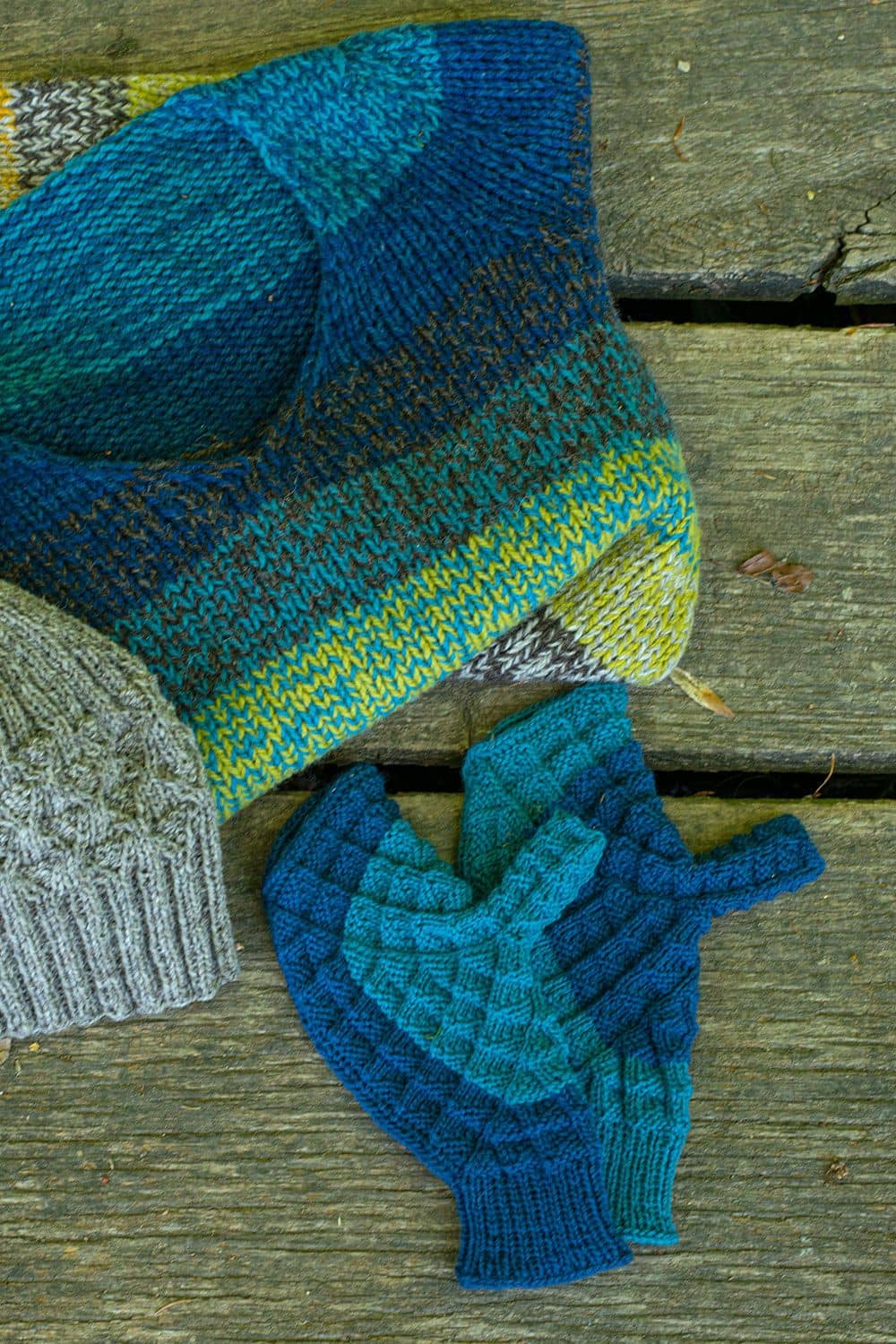 blau grüne Handschuhe neben Strickpulli als Projektbeispiel für Buch ,,Japanische Handschuhe stricken"