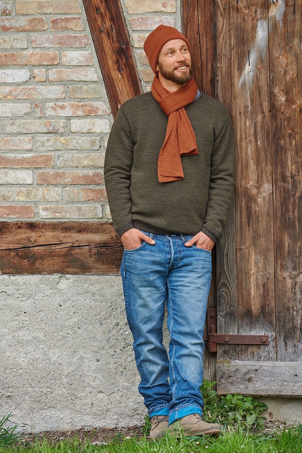 Mann mit grünem Pulli trägt eine orange leichte Mütze aus bio Wolle (kbT) und bio Baumwolle (kbA) und einen Schal
