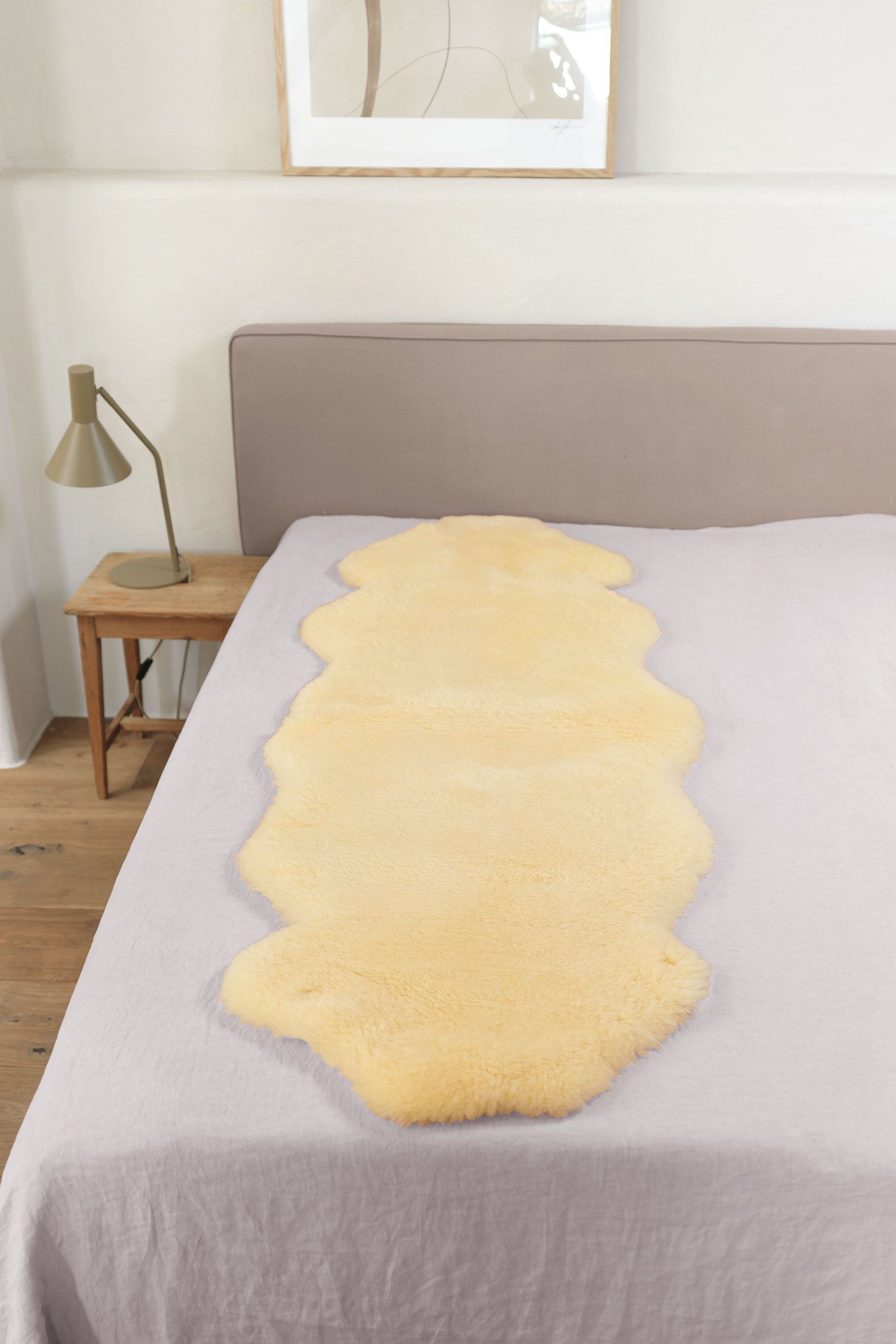 relugan gegerbte Felldecke in natürlicher Form aus Schaffell vom Finkhof auf grauem Bett