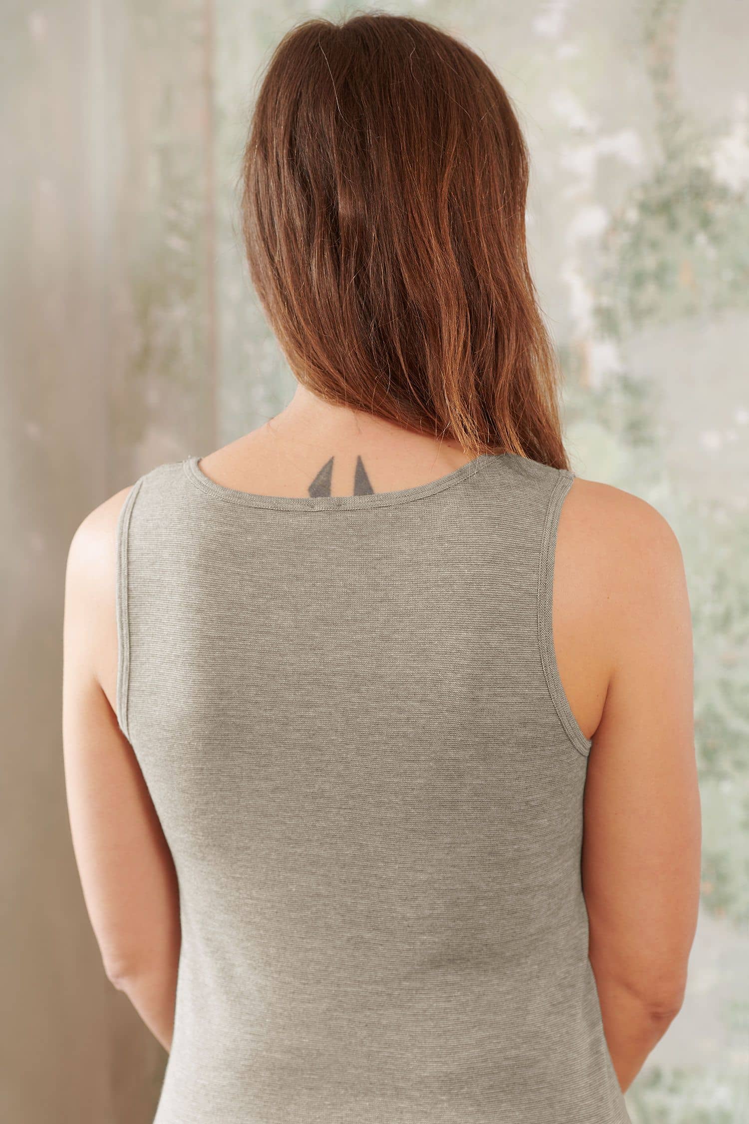 Frau trägt walnussbraunes Unterhemd vom Finkhof aus bio Baumwolle (kbA), Wolle (kbT) und Seide, von hinten fotografiert
