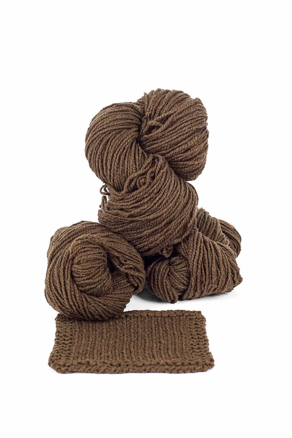 Finkhof Merinowolle dick gefärbt walnuss dicke walnussbraune Finkhof Merinowolle aus bio Wolle (kbT) mit Strickstück davor, weißer Untergrund