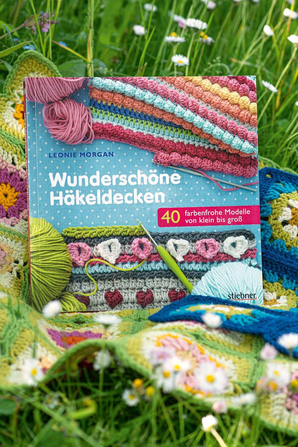 Wunderschöne Häkeldecken Buch ,,Wunderschöne Häkeldecken" auf bunter Häkeldecke im Gras