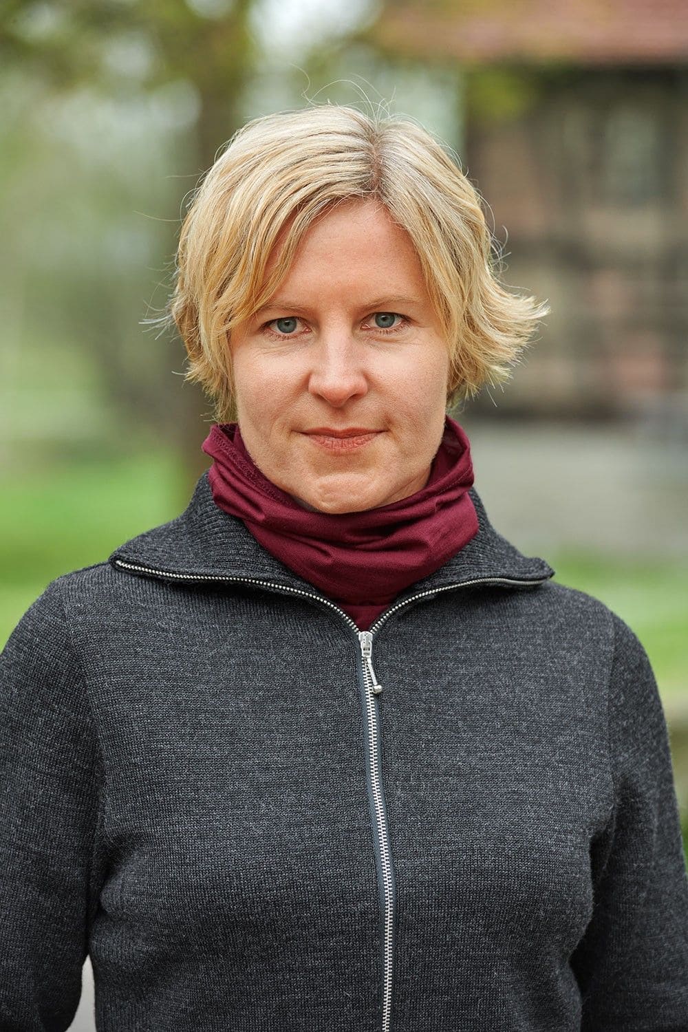 Sportschal bordeaux Frau mit grauer Weste trägt einen bordeauxroten Sportschal aus bio Wolle (kbT) und Seide