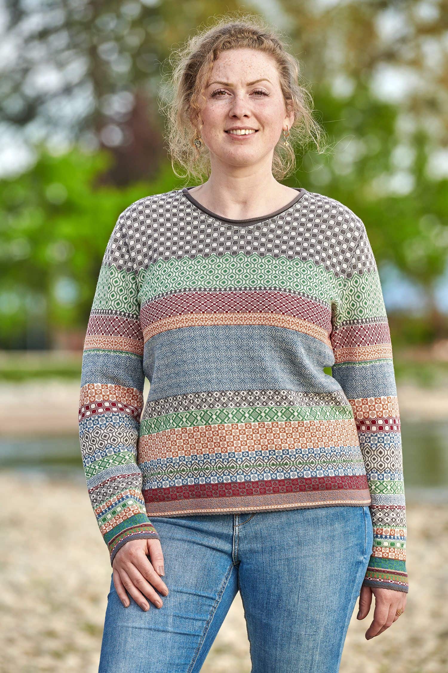 Frau trägt eine Jeans und einen gemusterten Strickpullover aus bio Baumwolle (kbA)