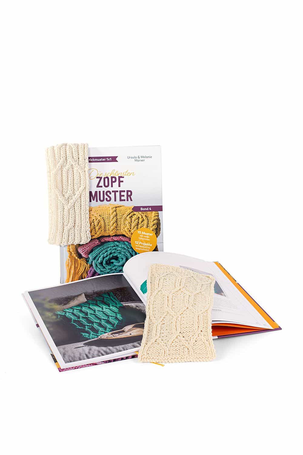 Die schönsten Zopfmuster Buch ,,Die schönsten Zopfmuster" mit aufgeschlagenem Exemplar davor und einem Strickprojekt