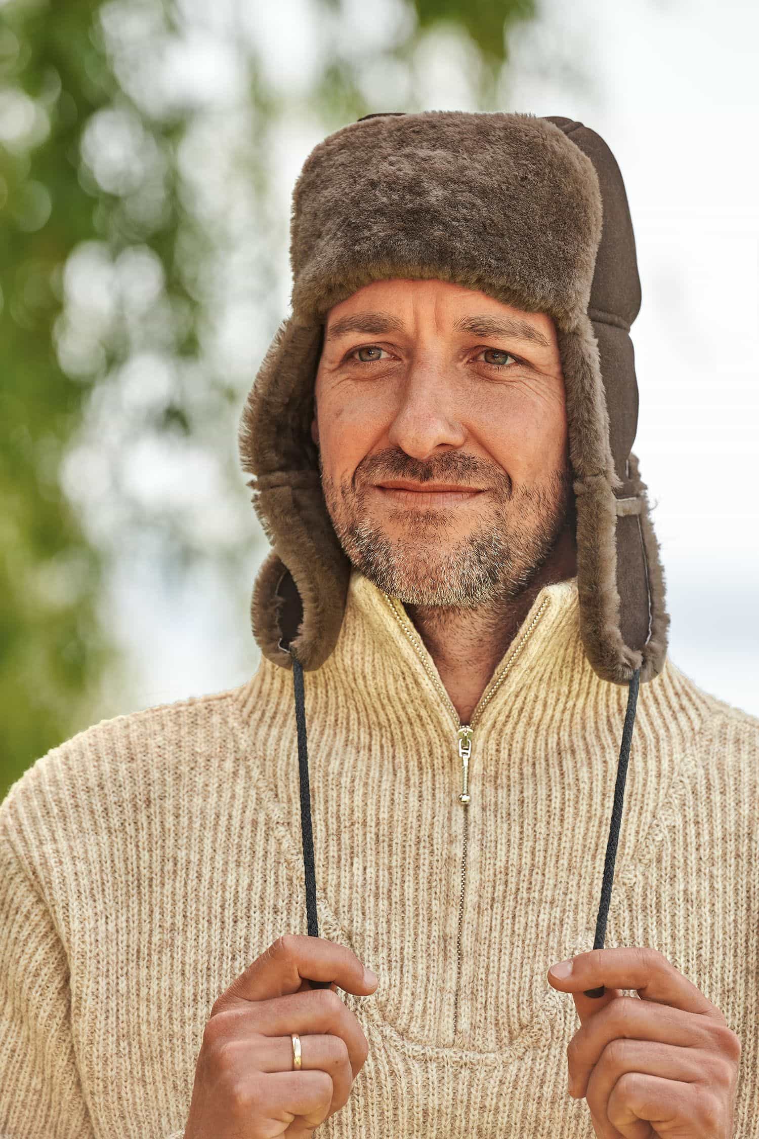 Fellmütze Mann mit Finkhof Troyer trägt eine braune Fellmütze aus Schaffell vom Finkhof
