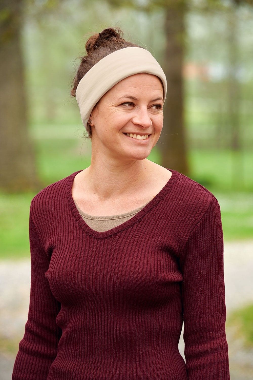 Frau mit rotem Rippshirt trägt naturweißen Sportschal aus bio Wolle (kbT) und Seide als Stirnband