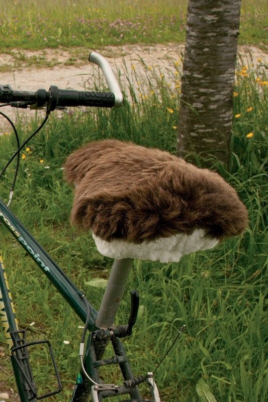 brauner breiter pflanzlich gegerbter Sattelbezug vom Finkhof aus bio Wolle (kbT) und Schaffell auf rotem Fahrrad von hinten