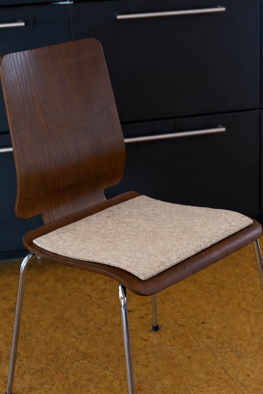 graue eckige Finkhof Sitzauflage aus bio Wolle (kbT) auf einem Holzstuhl