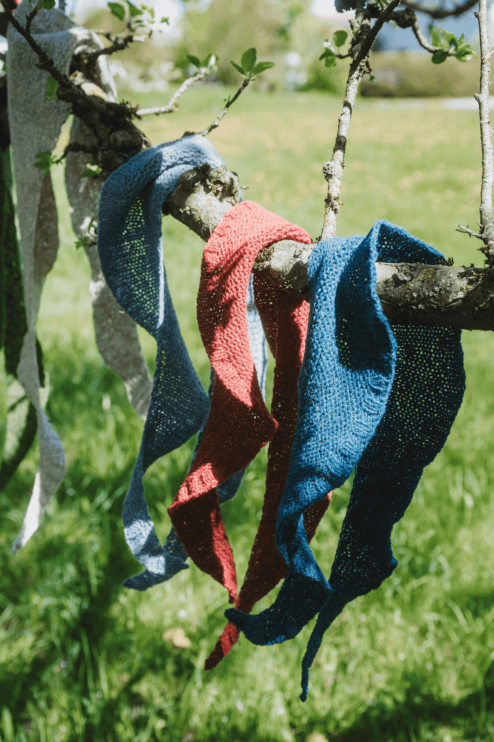 Schaltücher gestrickt aus gedeckten Finkhof Wollen hängen über einem Ast