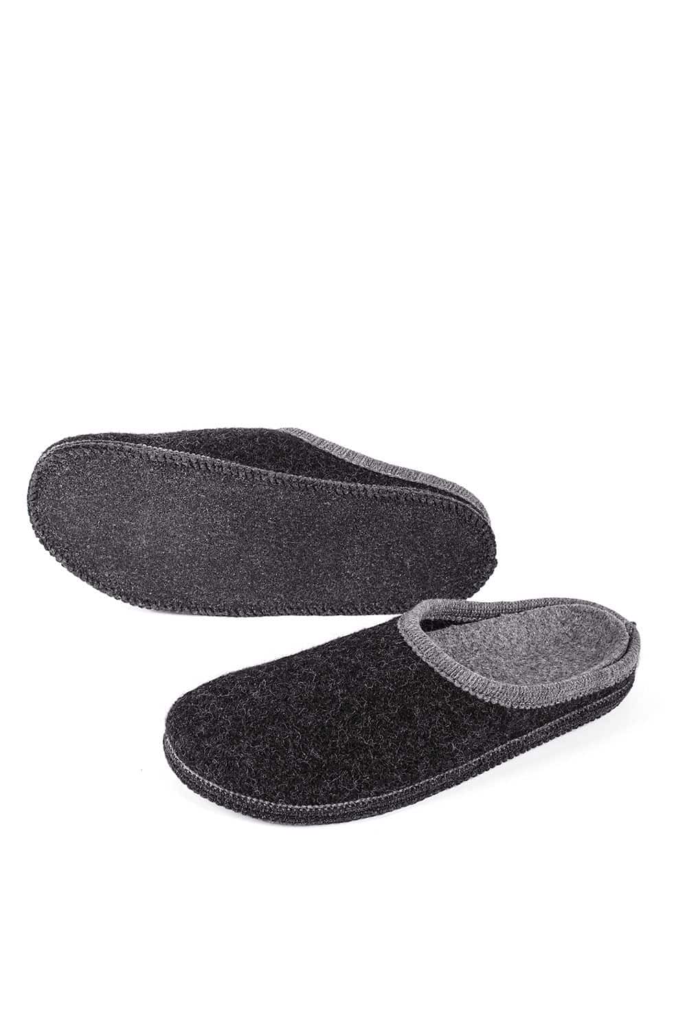 ein Paar anthrazitfarbene Pantoffeln mit Korkfußbett ein Schuh von der Seite der Andere von unten, auf weißem Untergrund