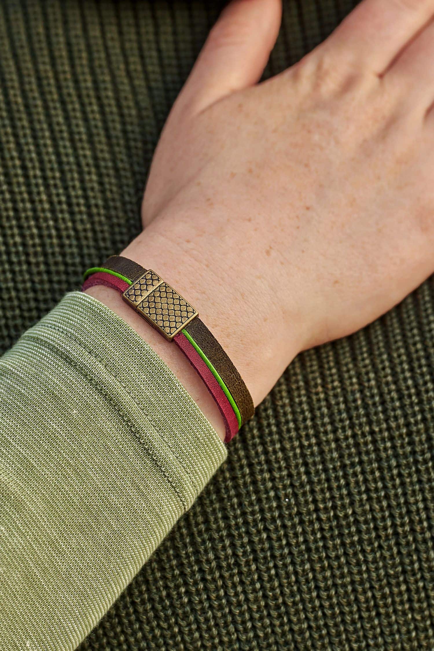 Frau mit grünem Pulli trägt ein Lederarmband olive aus Rinds- und Ziegenleder in rot, braun, grün