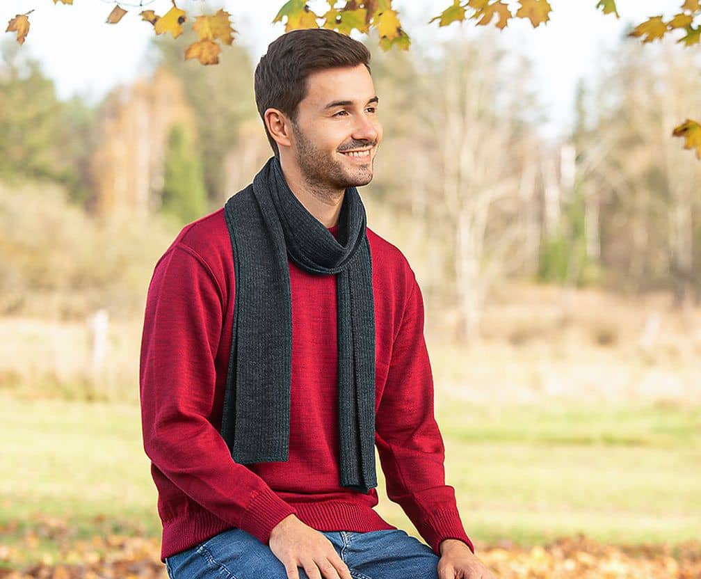 Finkhof Motiv Naturmode Herren mit einem Mann der mit rotem Pullover und grauem Schal dasitzt