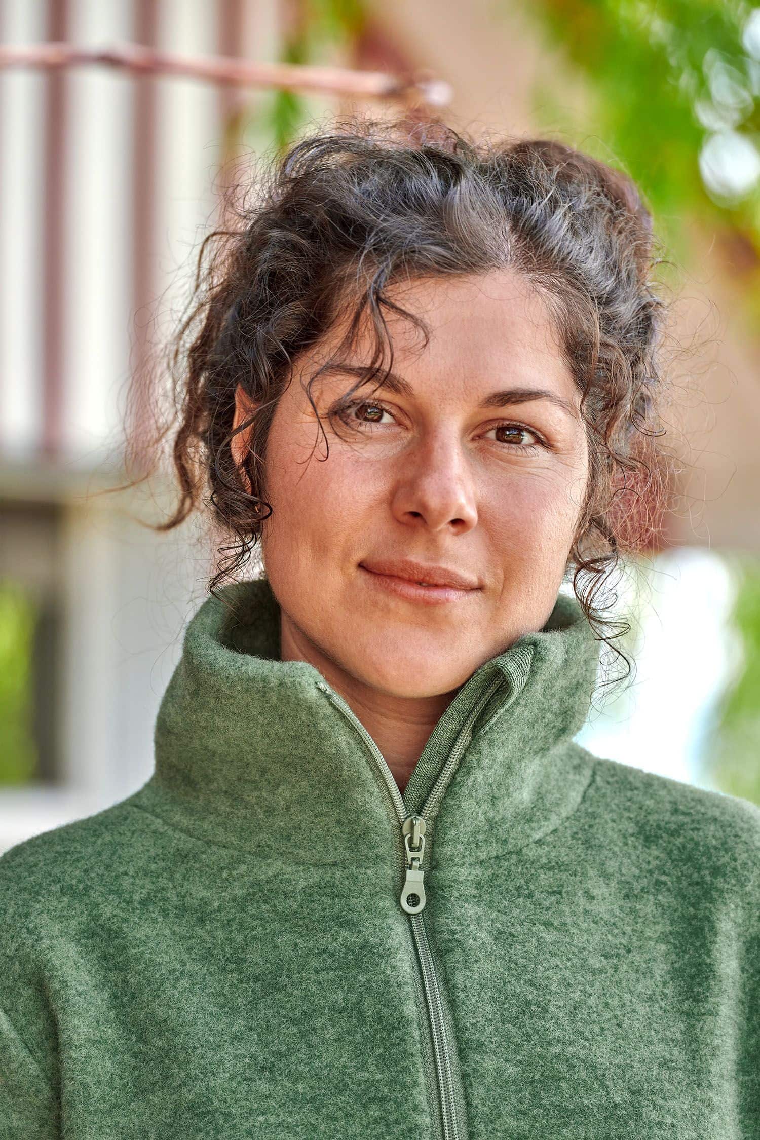 Portraitaufnahme von Frau mit grünem Pulli mit hohem Kragen und Reißverschluss aus bio Wolle (kbT) vom Finkhof