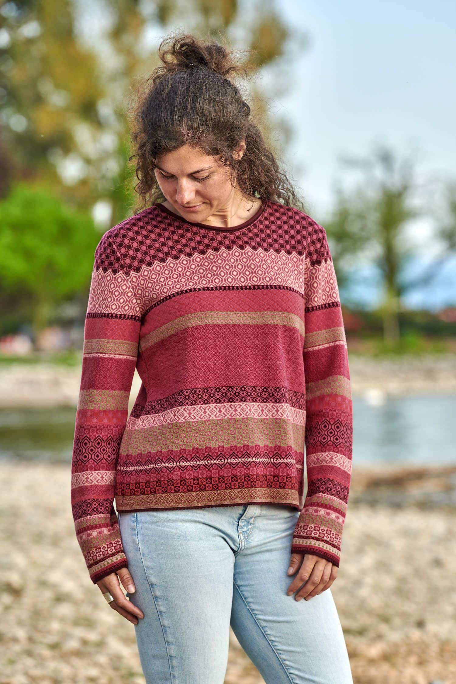 Frau trägt eine Jeans und einen Strickpullover mit Muster in beere und pink aus bio Baumwolle (kbA)