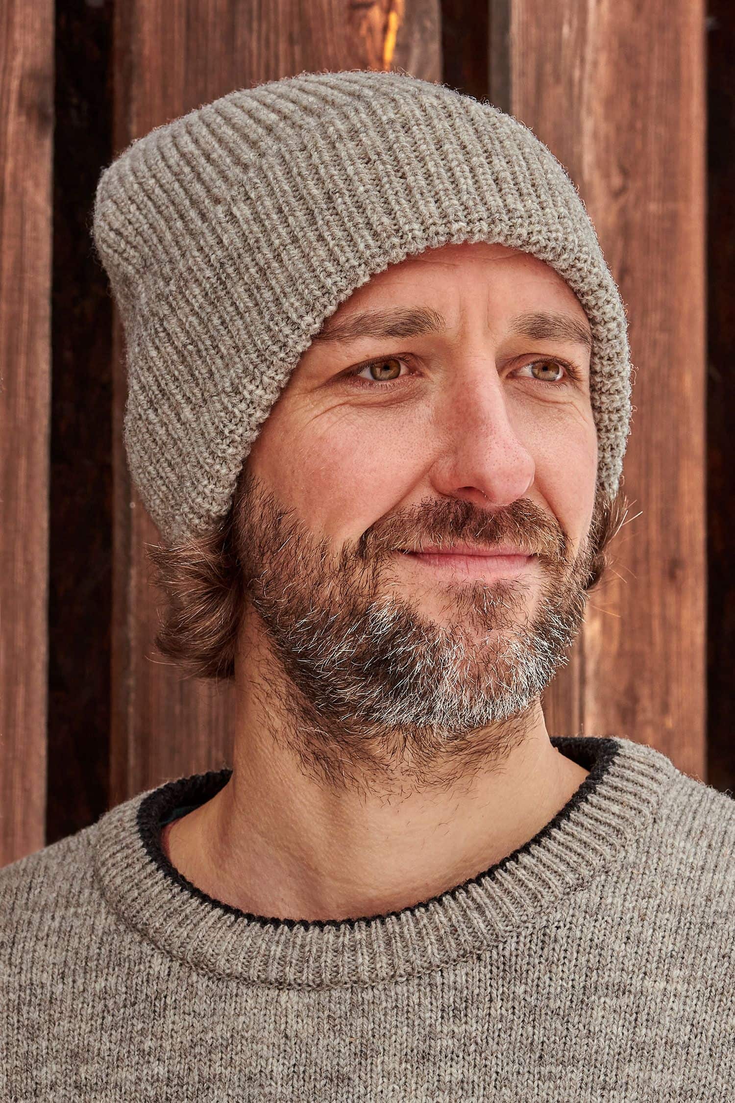 Portraitaufnahme von Mann mit grauer Finkhof Mütze aus bio Wolle (kbT) und grauem Pulli
