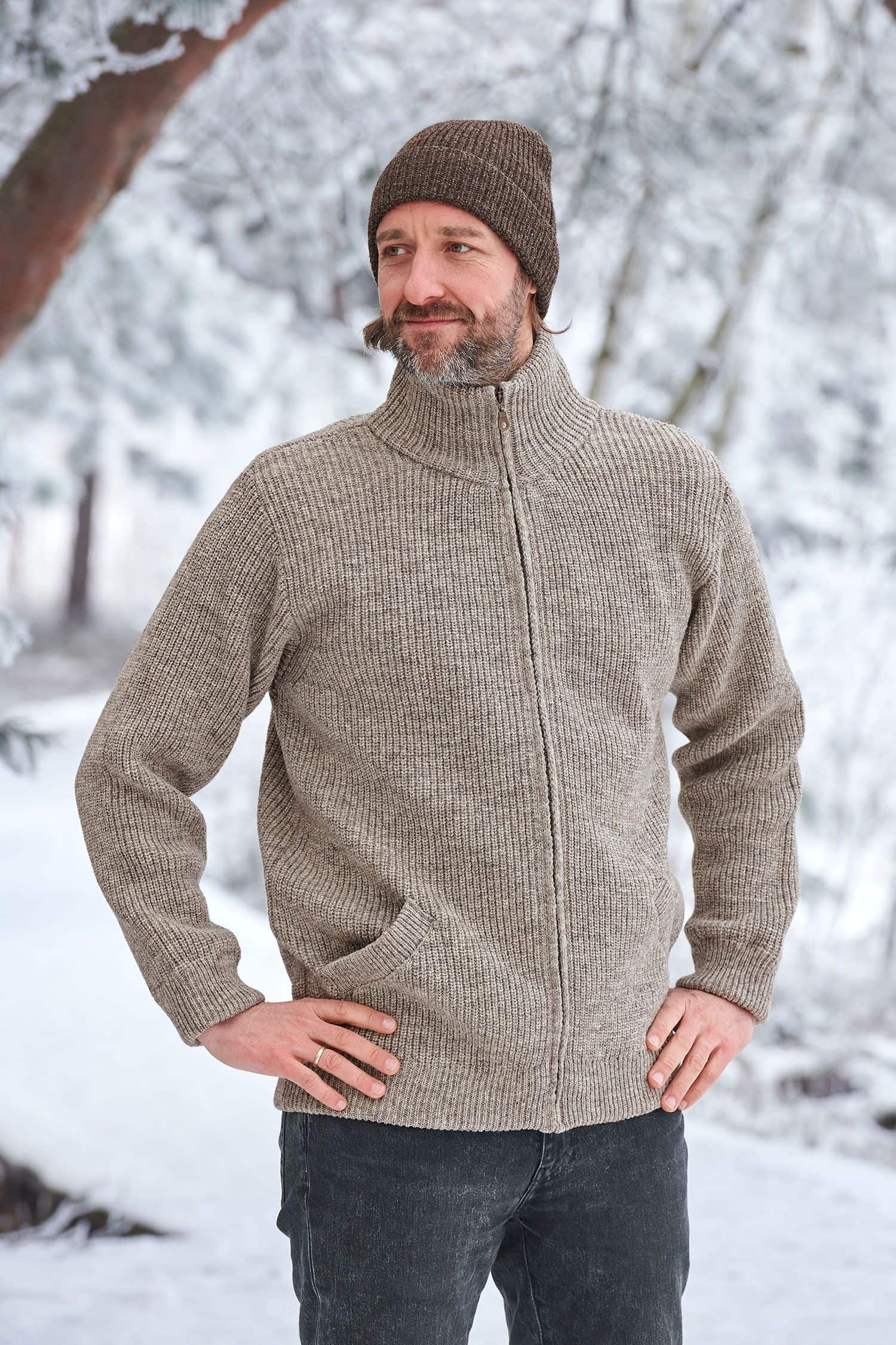 Mann in Schneelandschaft trägt eine graue Finkhof Jacke aus bio Wolle (kbT) und eine braune Mütze