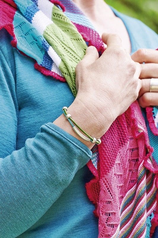 Frau mit türkisem Shirt und buntem Schal trägt ein Lederarmband aus pflanzlich gegerbtem Rinds- und Ziegenleder