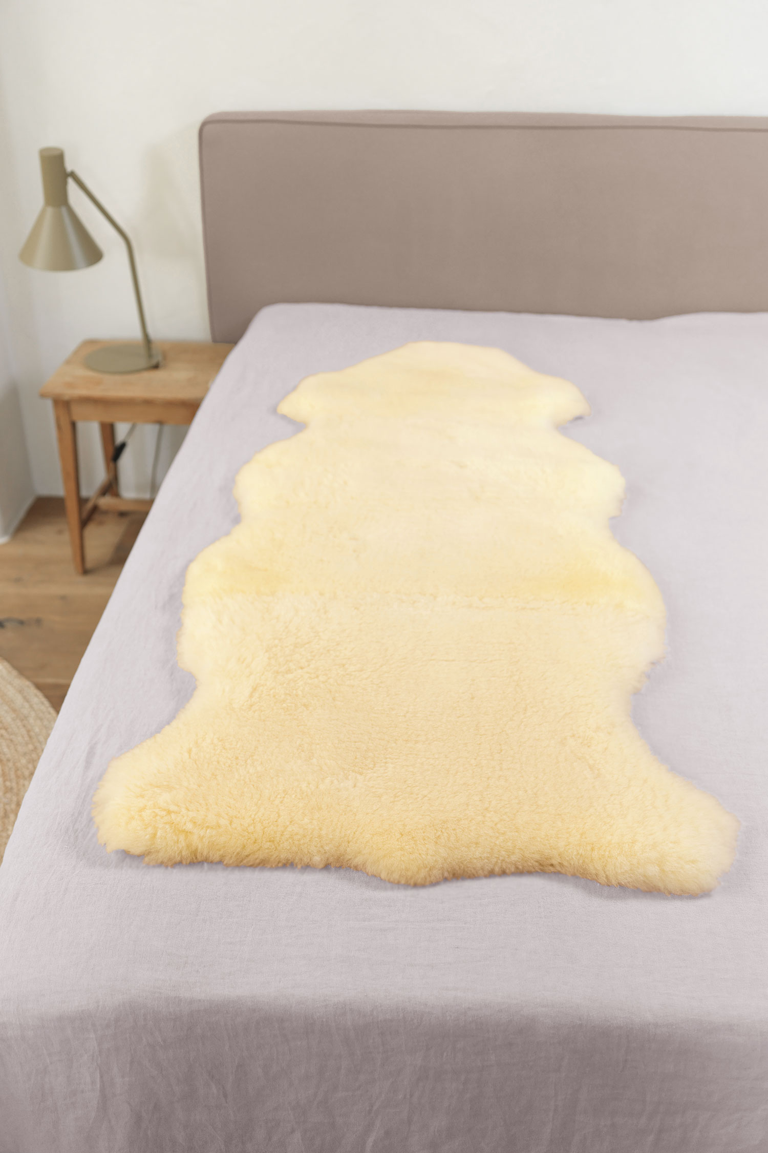 relugan gegerbte Felldecke in natürlicher Form aus Schaffell vom Finkhof auf grauem Bett