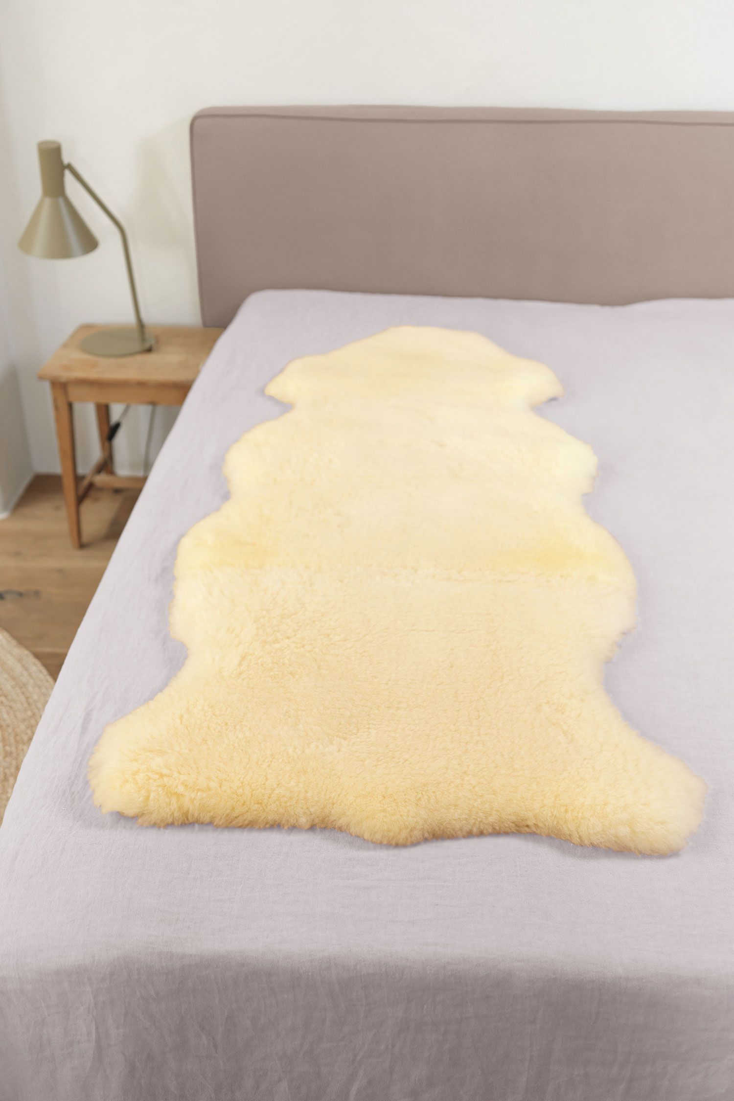 relugan gegerbte Felldecke in natürlicher Form aus Schaffell vom Finkhof auf grauem Bett