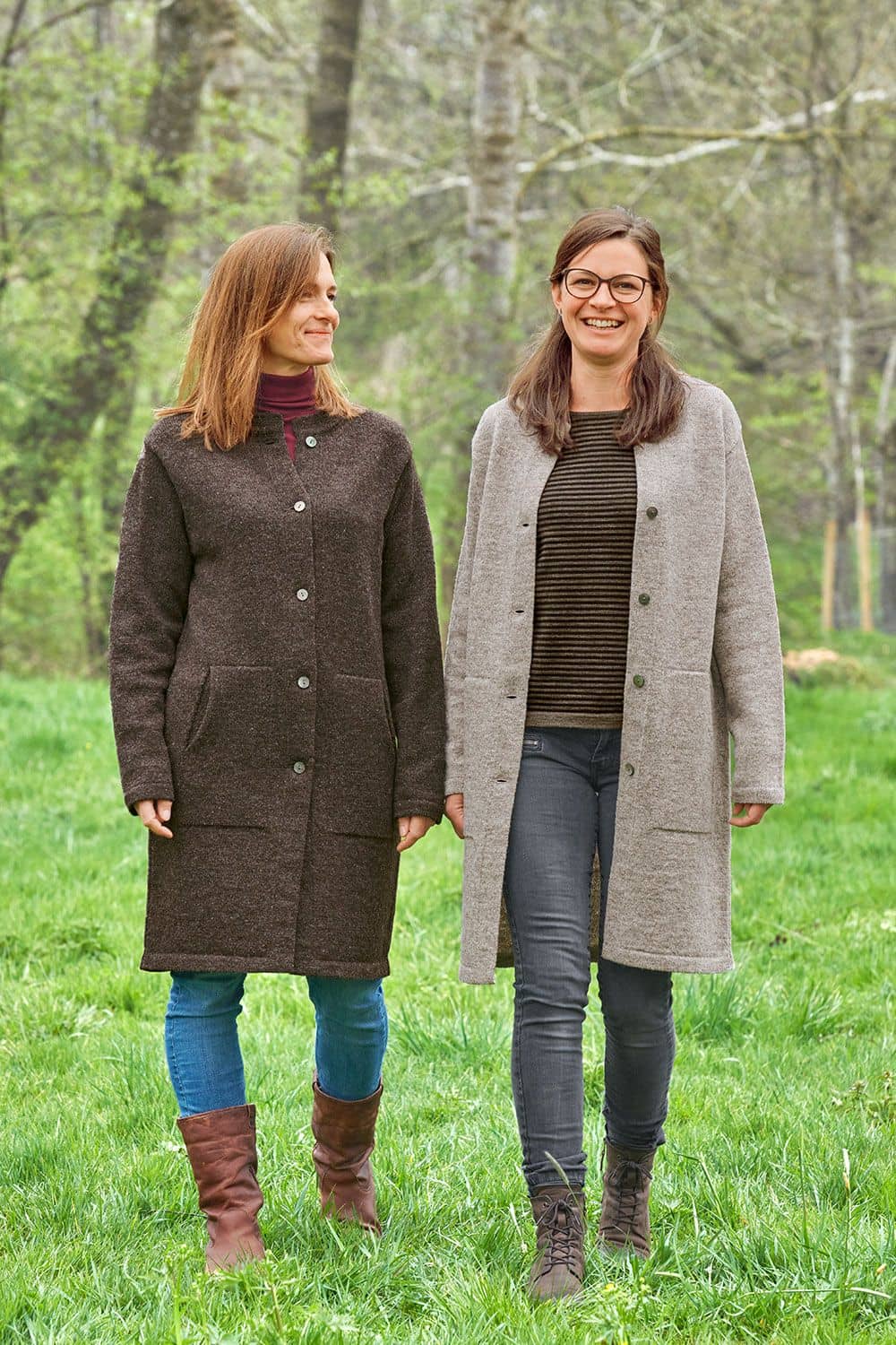 Finkhof-Strickmantel Frauen auf Wiese tragen braunen und grauen Finkhof Strickmantel aus bio Wolle (kbT) mit Jeans und Stiefeln
