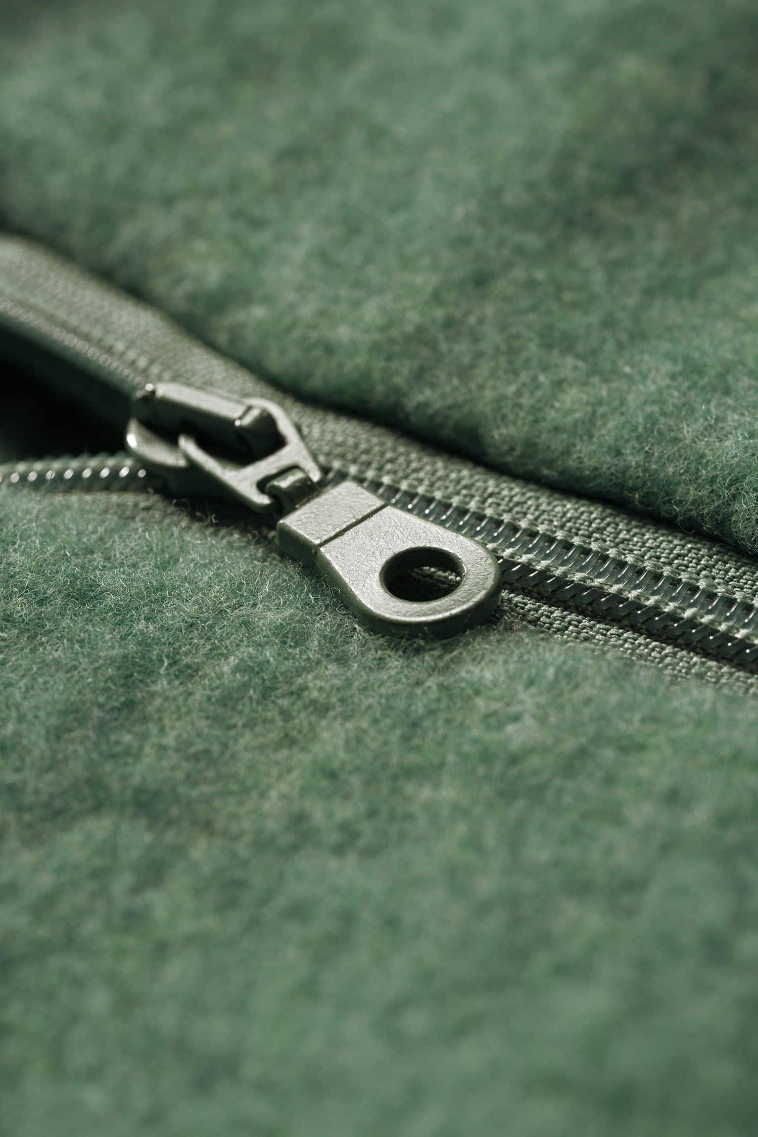 Detailaufnahme vom Reißverschluss des grünen Wollfleecepullis mit hohem Kragen aus bio Wolle (kbT) vom Finkhof