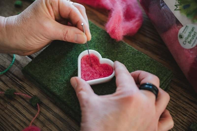 pinkes Herz wird auf grünem Filz trockengefilzt