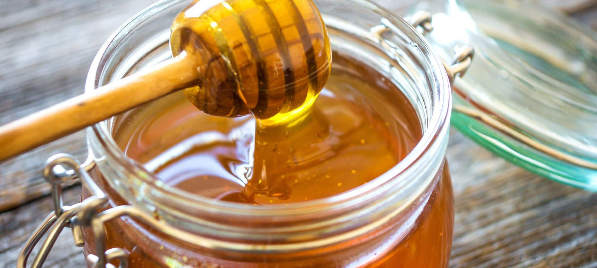 Finkhof Banner mit Nahaufnahme von geöffnetem Honigglas mit Honiglöffel