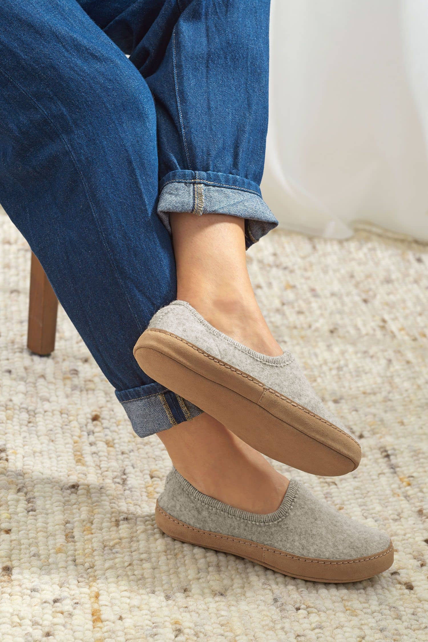 Person trägt hellgraue Finkhof Hausschuhe aus bio Wolle (kbT), Sohle aus pflanzlich gegerbtem Rindsleder, seitlich zu sehen