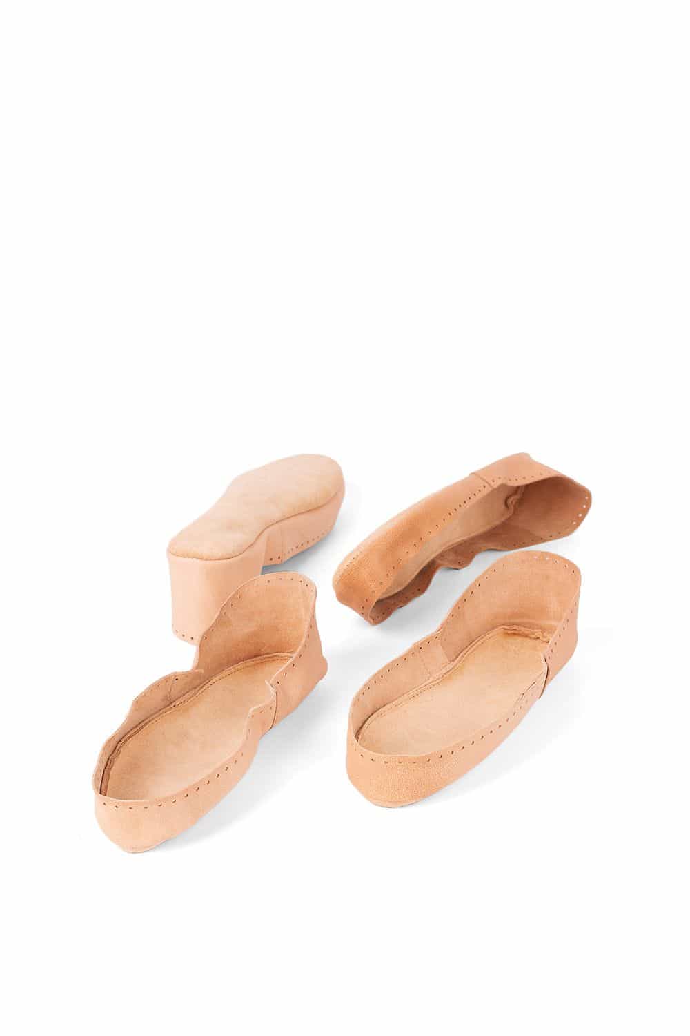 4 hellbraune Hüttenschuhsohlen aus pflanzlich gegerbtem Rindsleder in verschiedenen Positionen