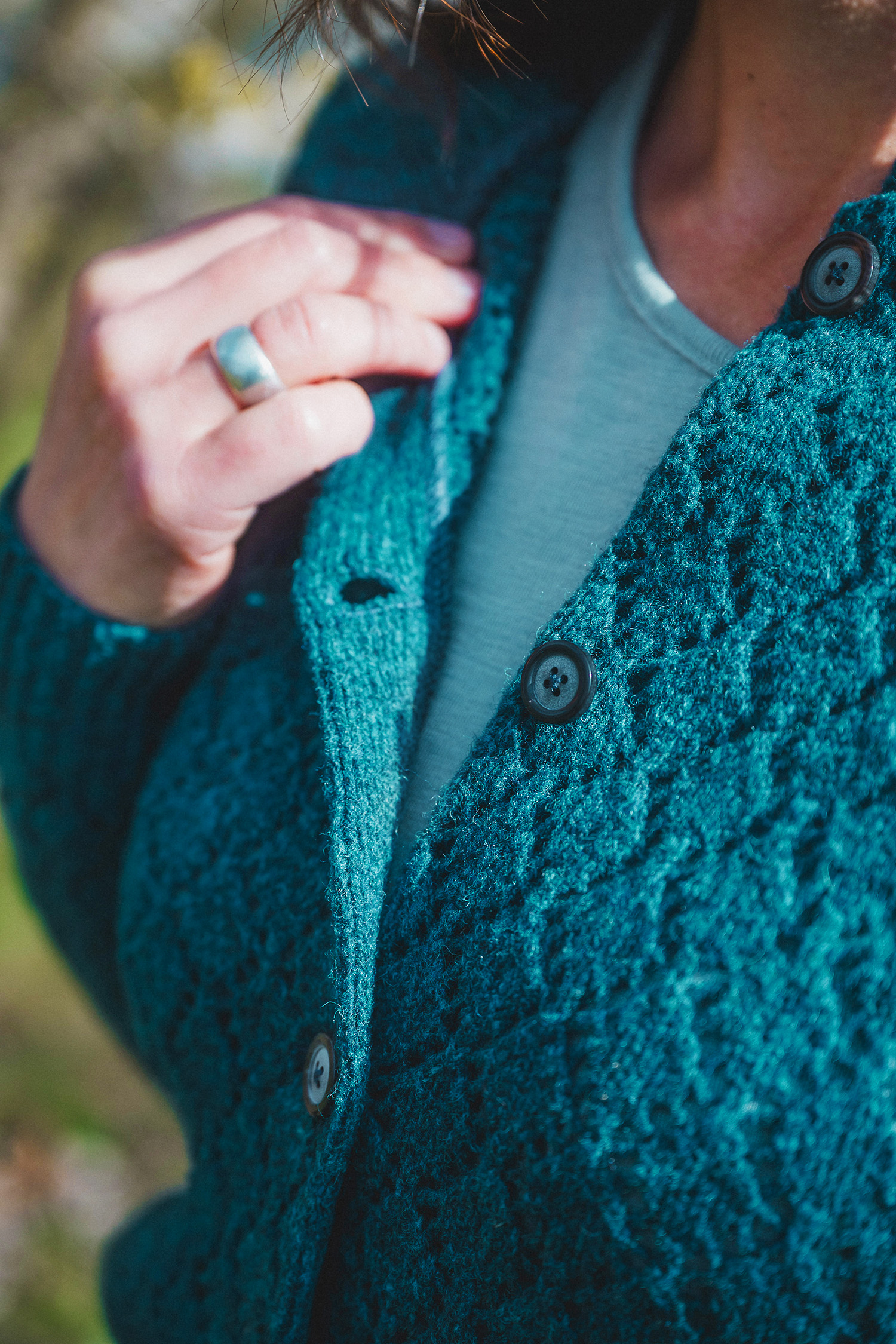 Nahaufnahme der Knopfleiste der blauen Damenstrickjacke mit Ajourmuster aus Bio-Wolle vom Finkhof
