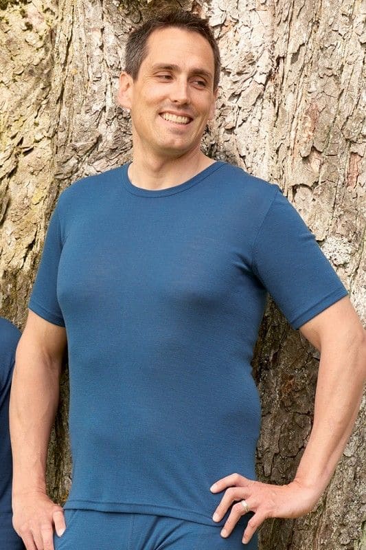 Mann leht an Baum und trägt dunkelblaues Kurzarmhemd aus bio Wolle (kbT) und Seide