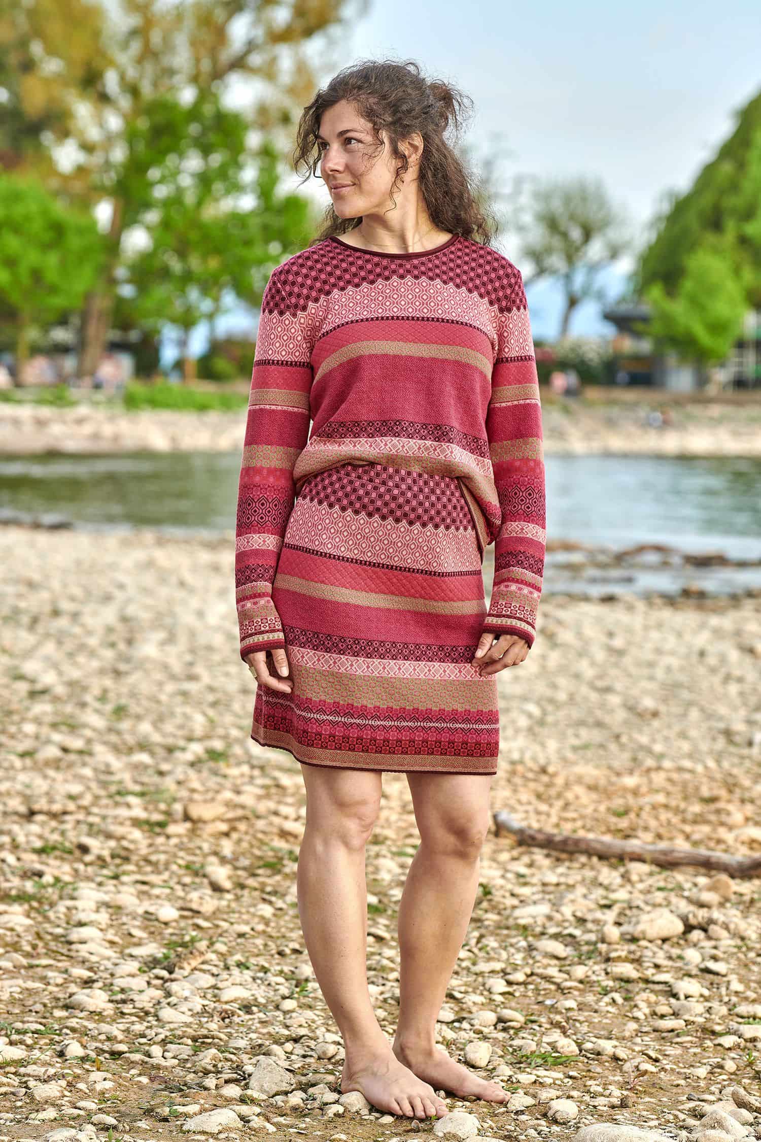 Frau trägt gemusterten Rock und Pulli in beere und pink aus bio Baumwolle (kbA)