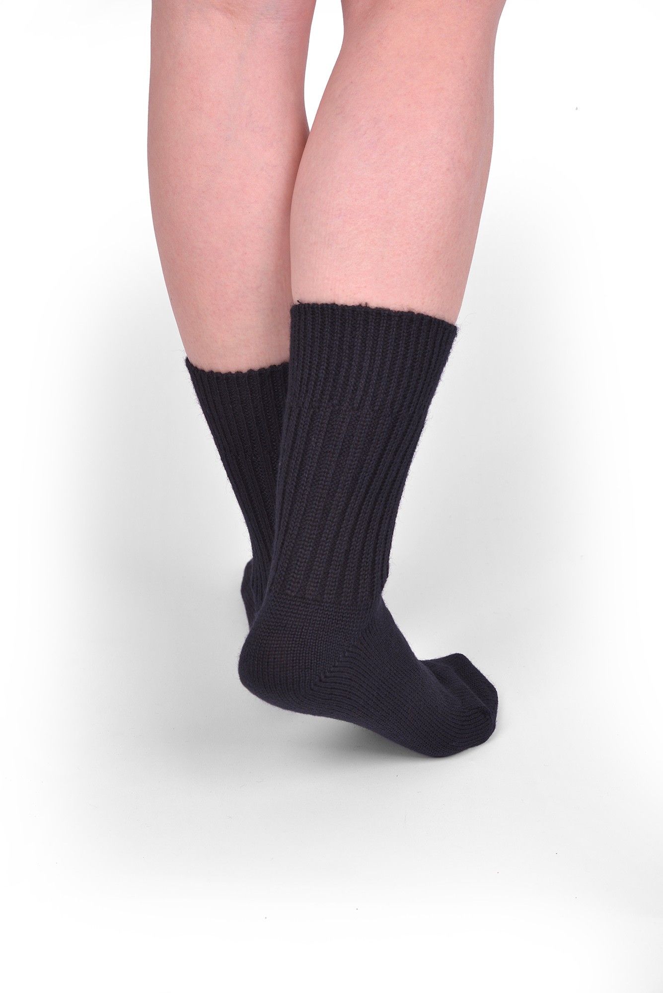 Person trägt schwarze Wollsocken aus bio Wolle (kbT) in mittlerer Dicke, von hinten