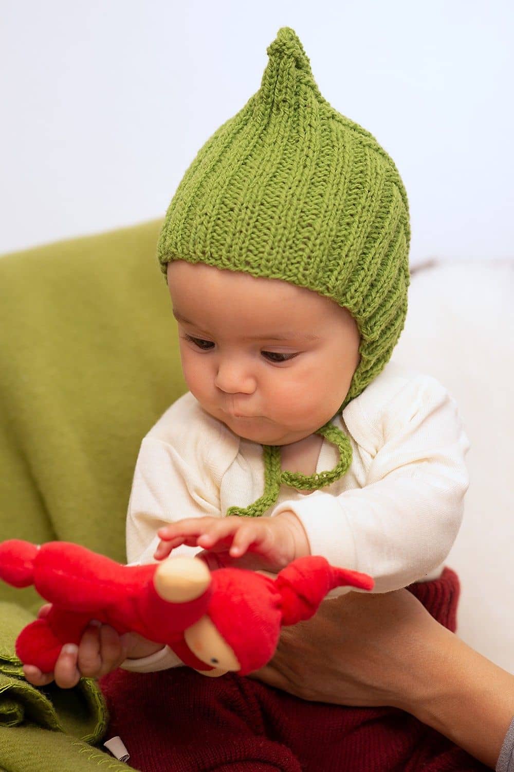 Baby trägt Strickmütze aus grüner Finkhof Merinowolle aus bio Wolle (kbT)