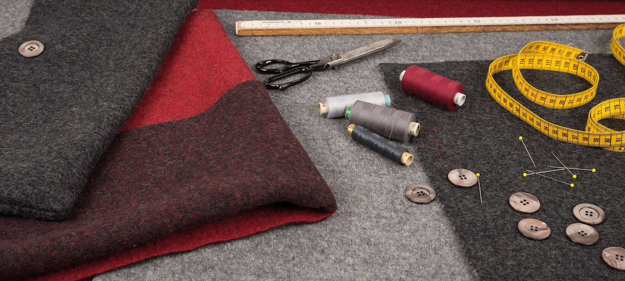 Finkhof Banner für Kissen mit grauen und roten Stoffen sowie Nähutensilien