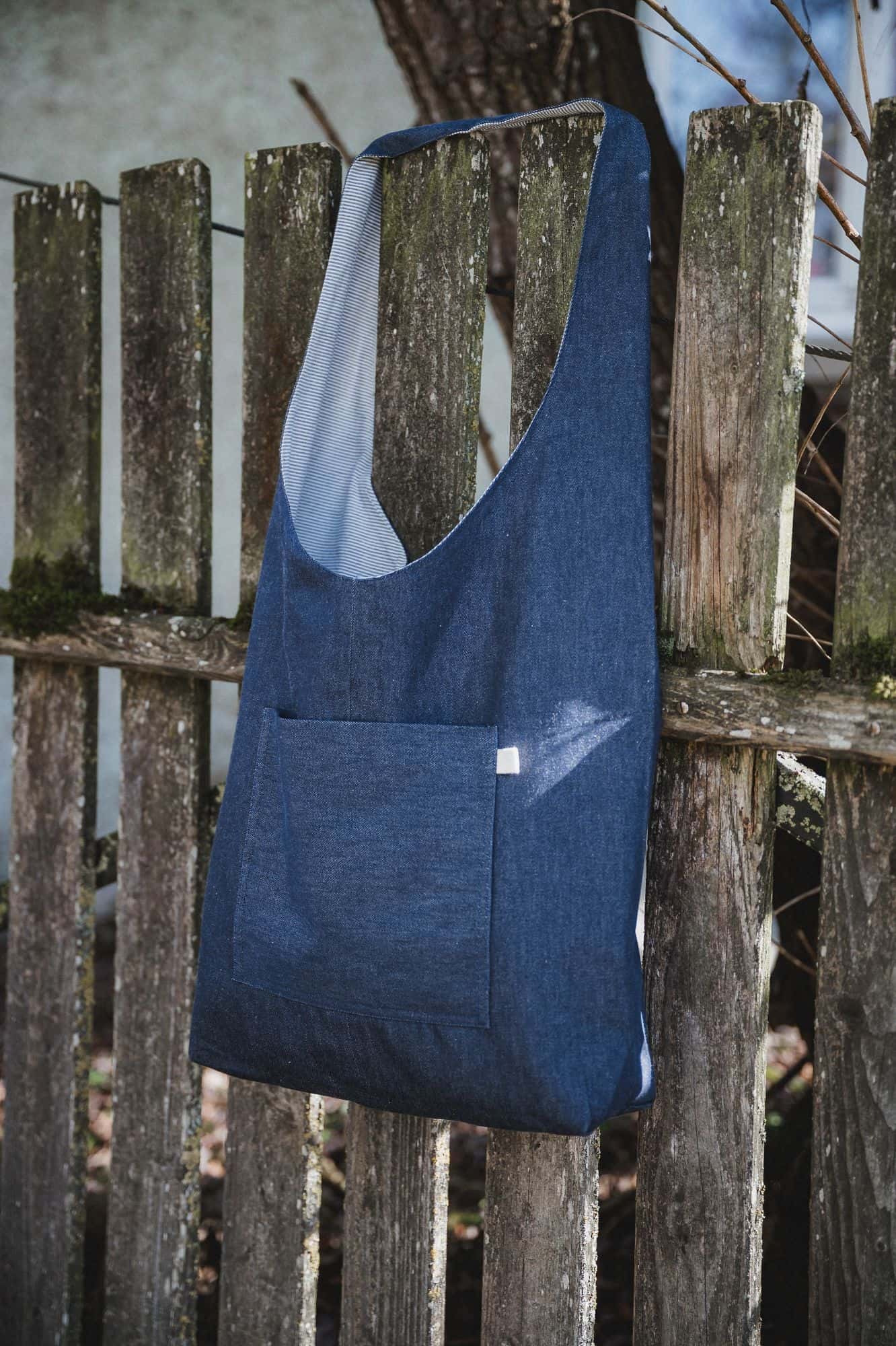 Bio-Baumwoll-Tasche zum Wenden Finkhof Wendetasche aus Bio-Baumwolle in blau und weiß hängt mit blauer Seite außen an einem Gartenzaun