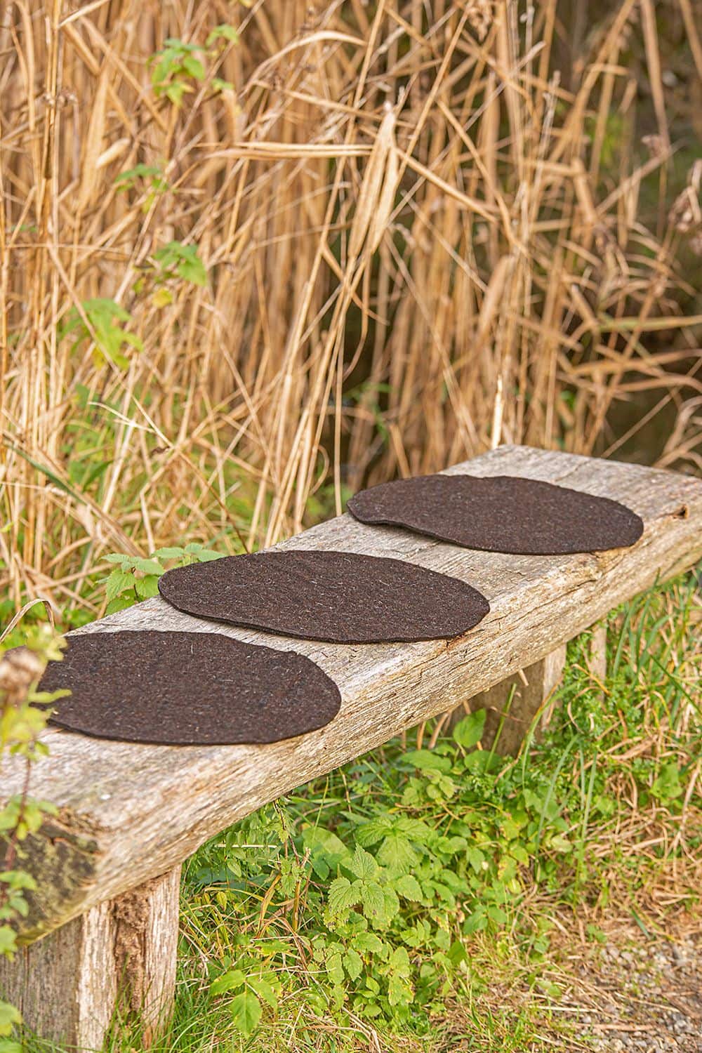 runde braune Sitzunterlagen aus Wollfilz von bio Finkhof Wolle (kbT) auf einer Bank