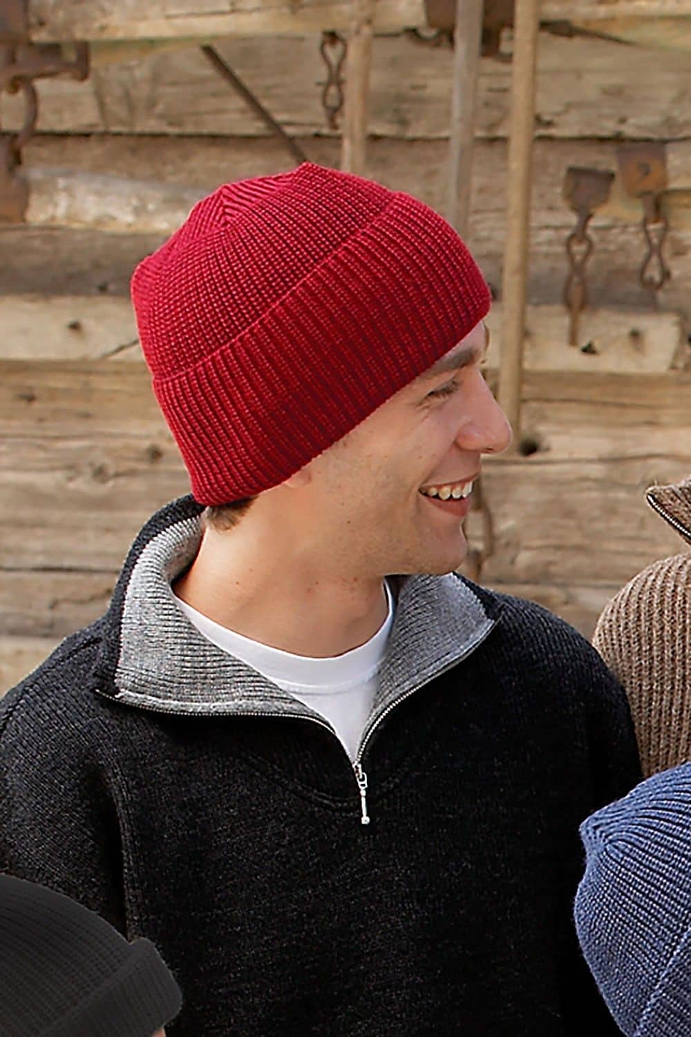 Mann trägt dunklen Finkhof Troyer und eine rote Wollmütze aus bio Wolle (kbT) vom Finkhof