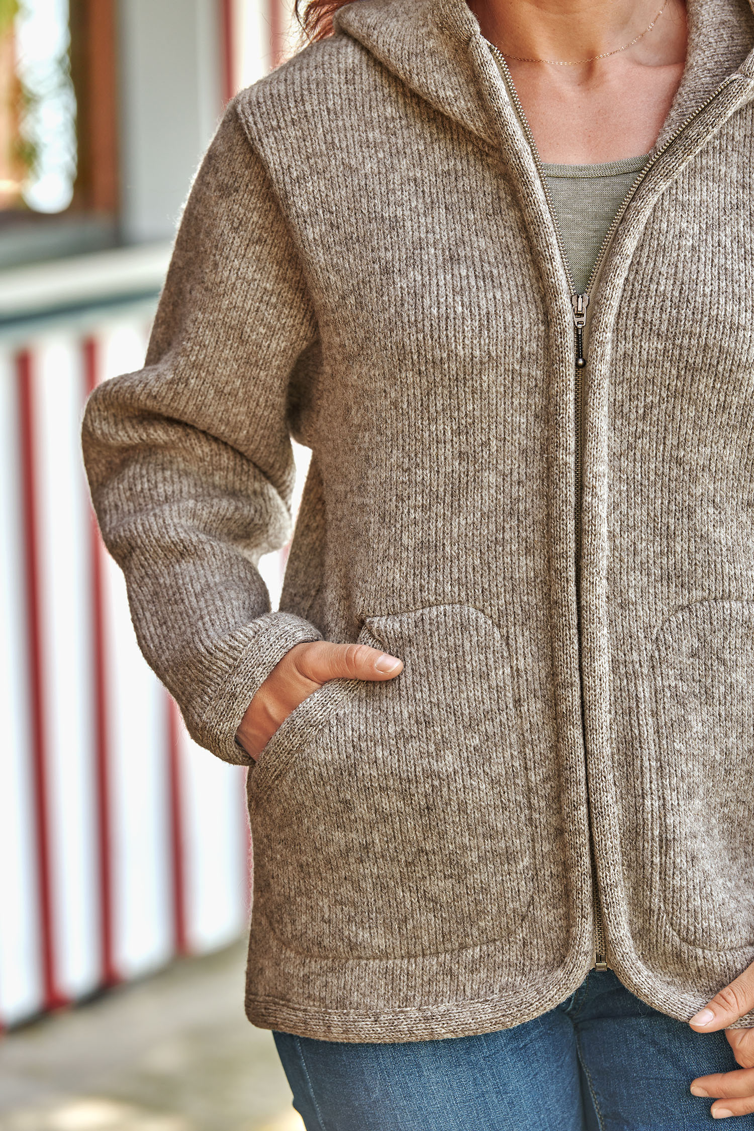 graue Kapuzenjacke vom Finkhof aus bio Wolle (kbT) wird mit Hände in den Taschen getragen