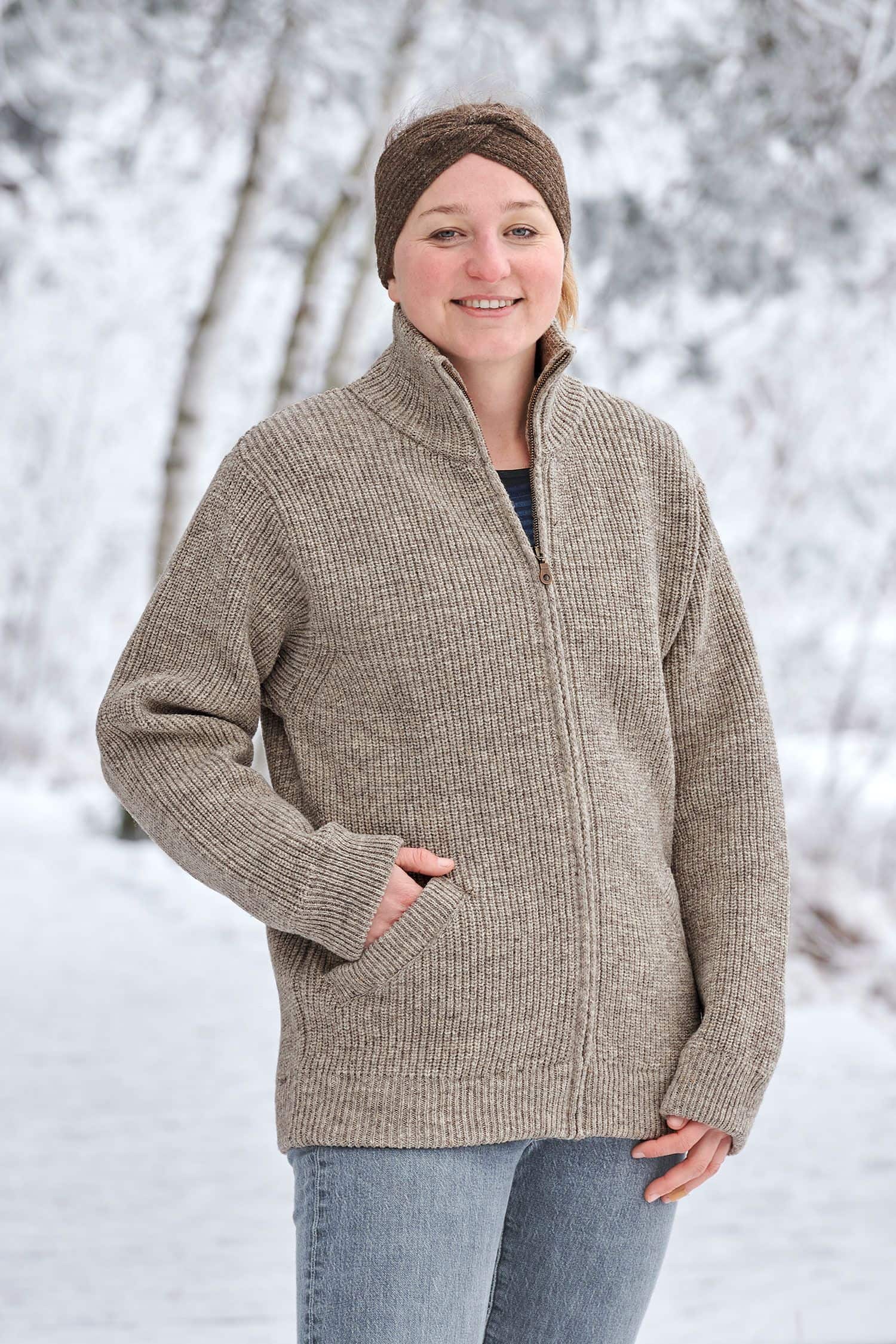 Frau in Schneelandschaft trägt graue Finkhof Jacke aus bio Wolle (kbT), braunes Stirnband mit Twist und Streifenshirt