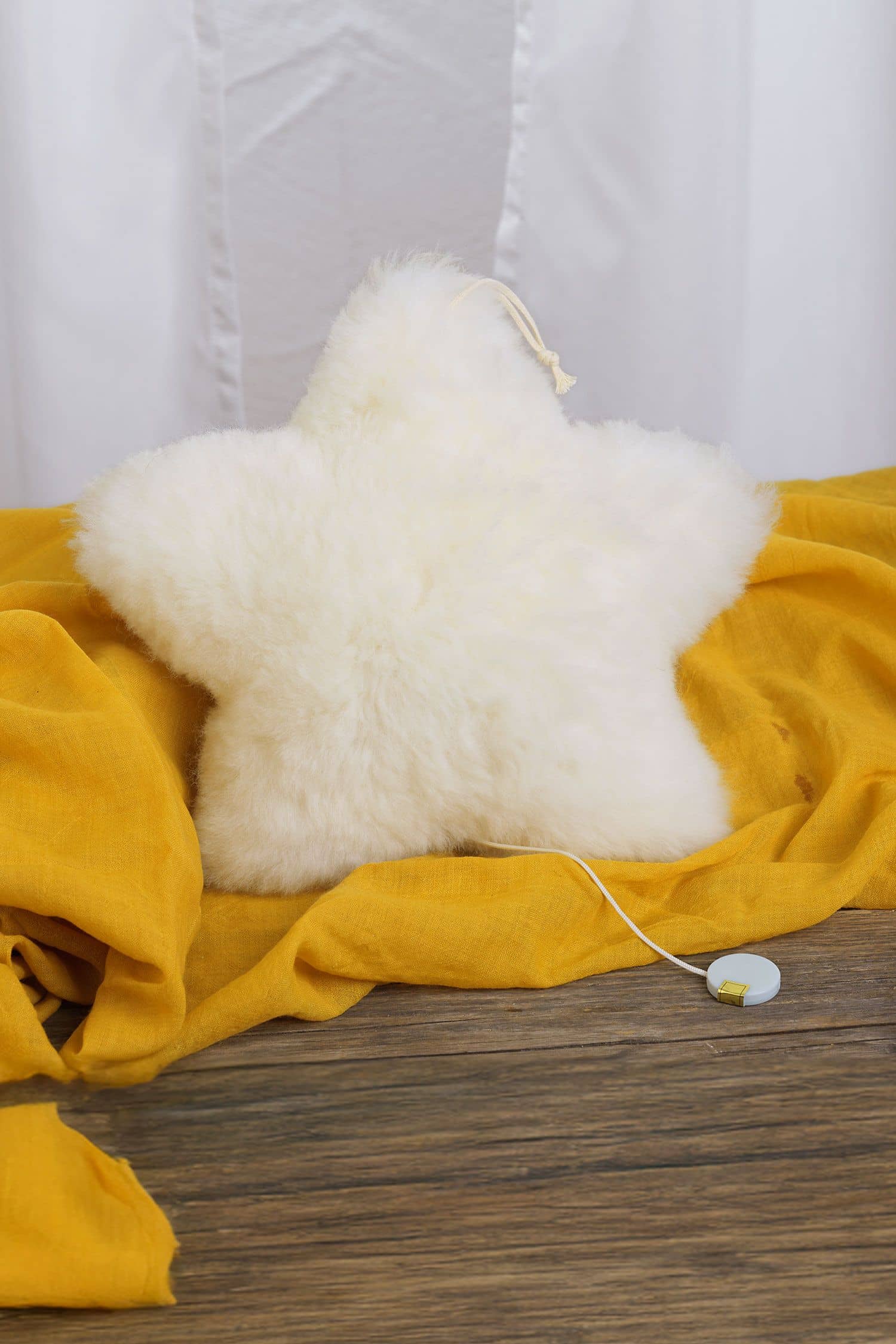 Spieluhr Stern weiße Spieluhr in Sternenform aus Schaffell mit bio Wolle (kbT) vom Finkhof auf gelber Decke