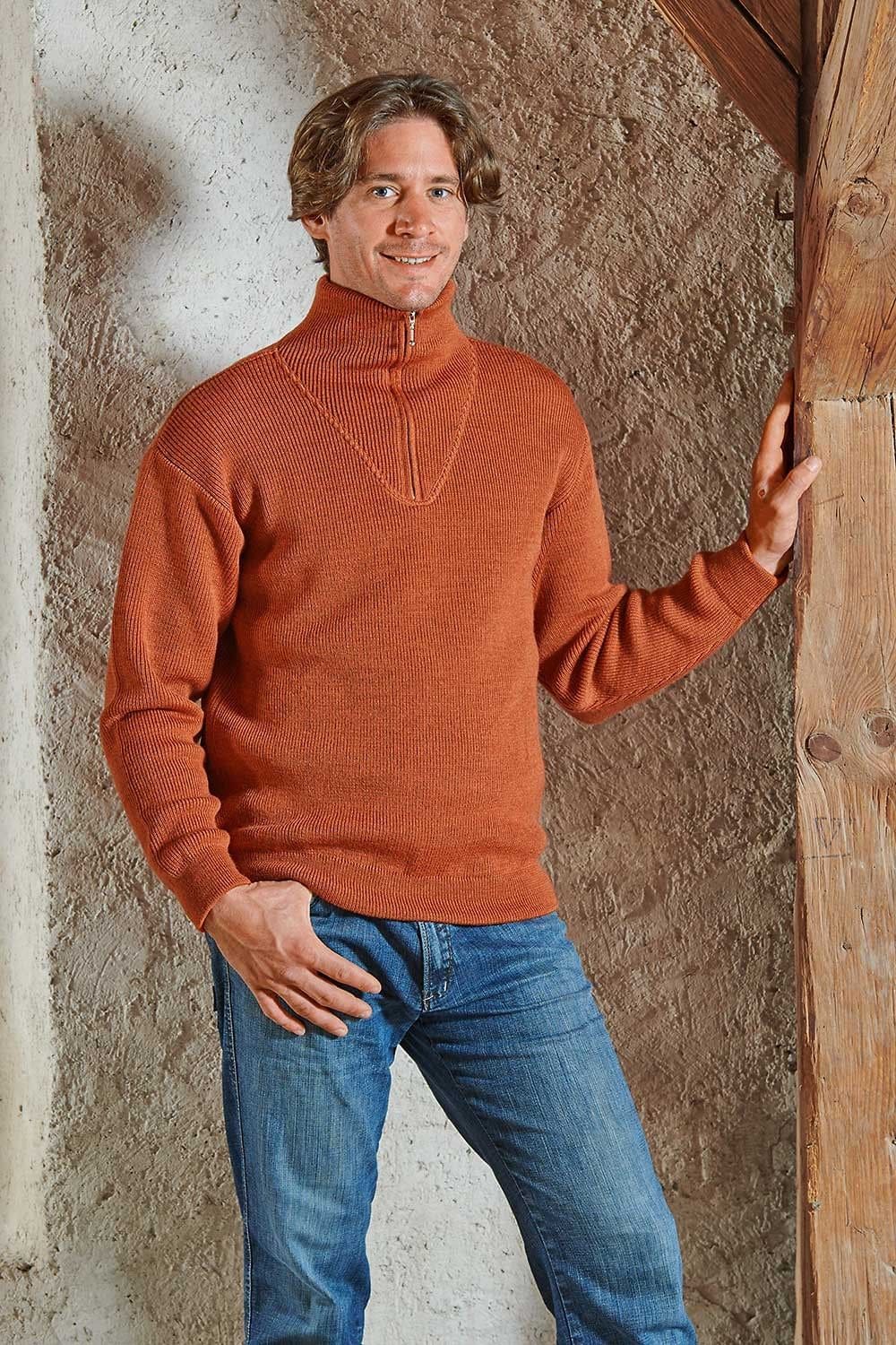 Mann trägt terrafarbenen Troyer mit Zipper aus bio Wolle (kbT) vom Finkhof und hält sich an Balken